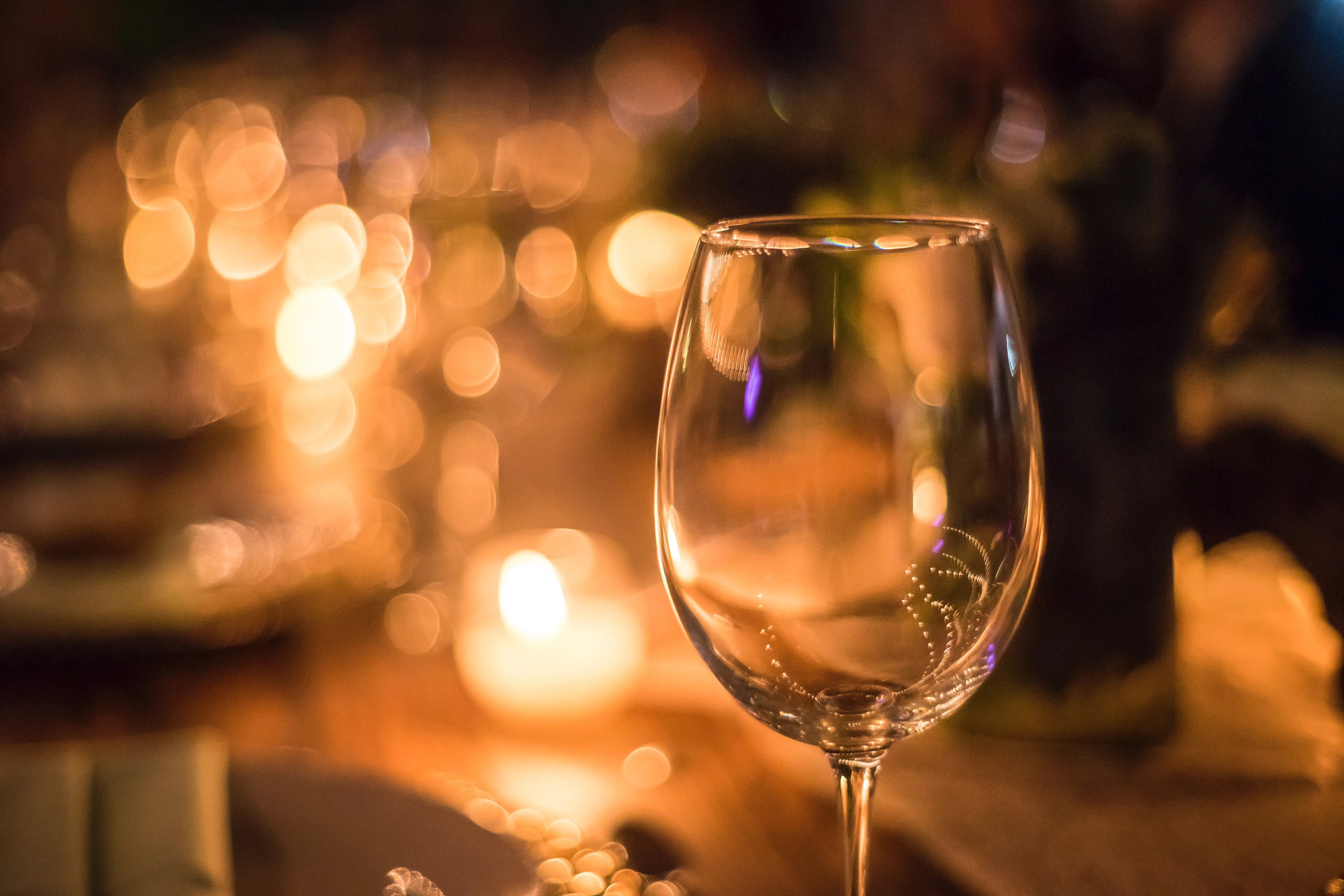 close up of wine glass with candlelight in background.