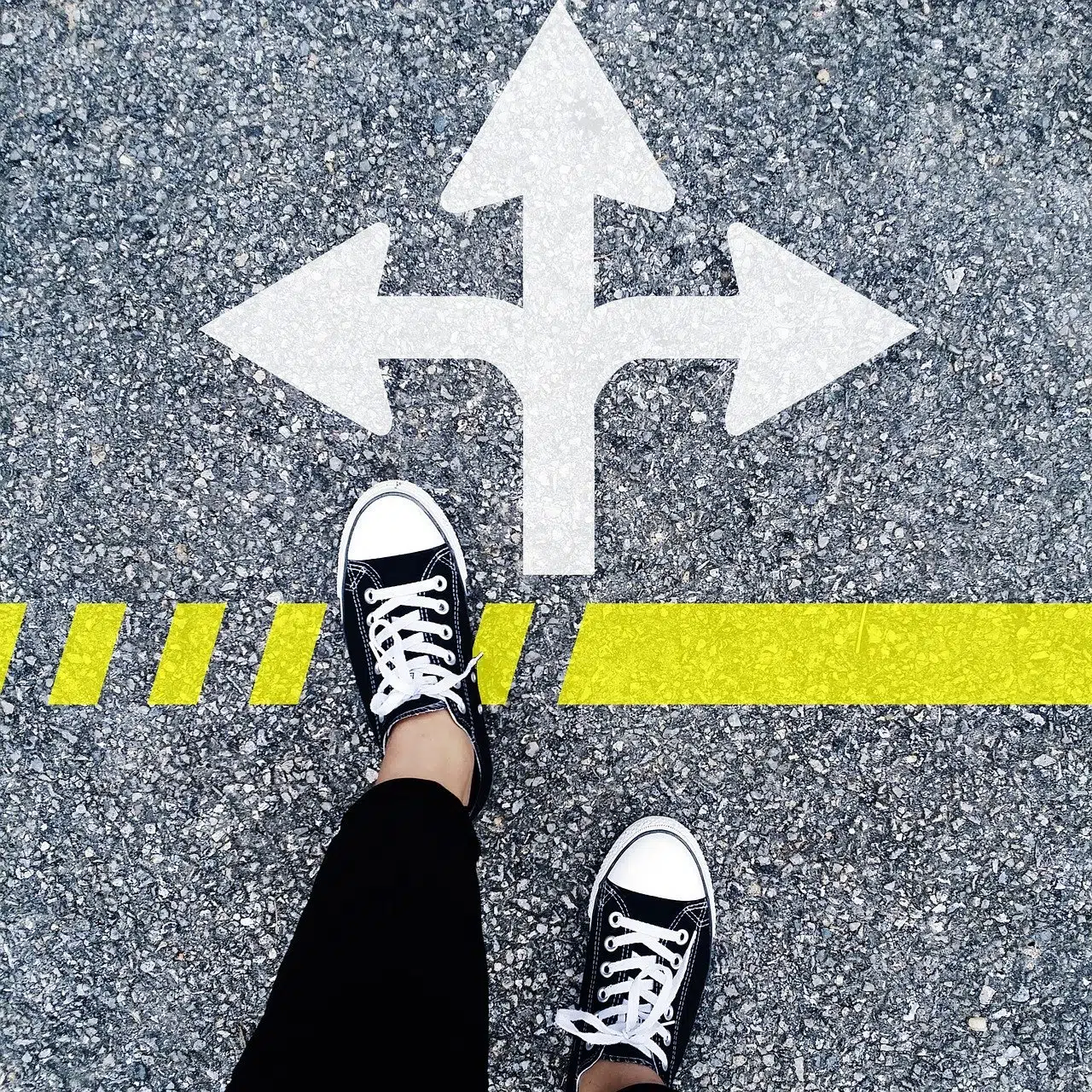looking down at feet standing at a symbol of three-arrows pointing in different directions.