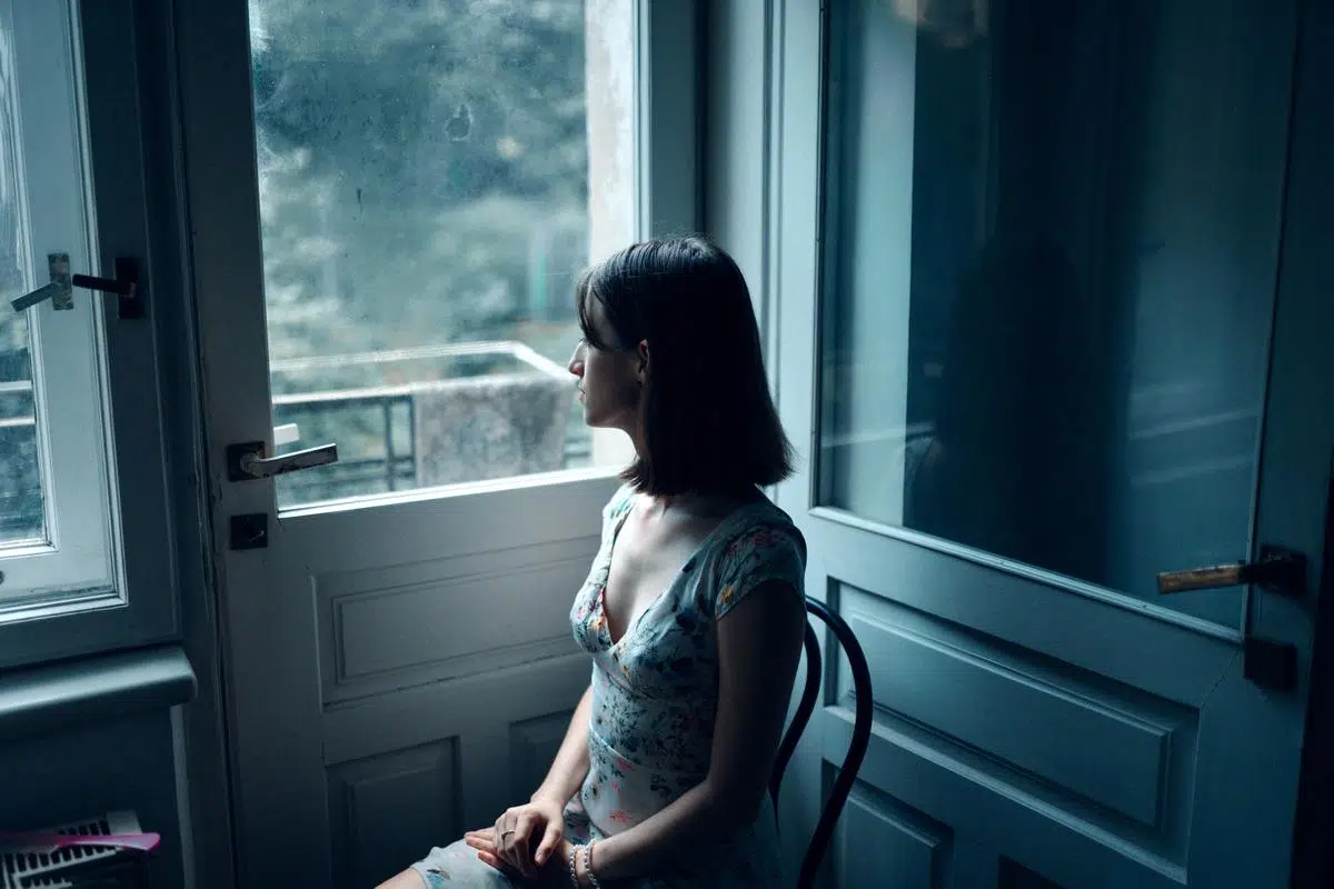 Sad woman sitting staring out window on a gloomy day.