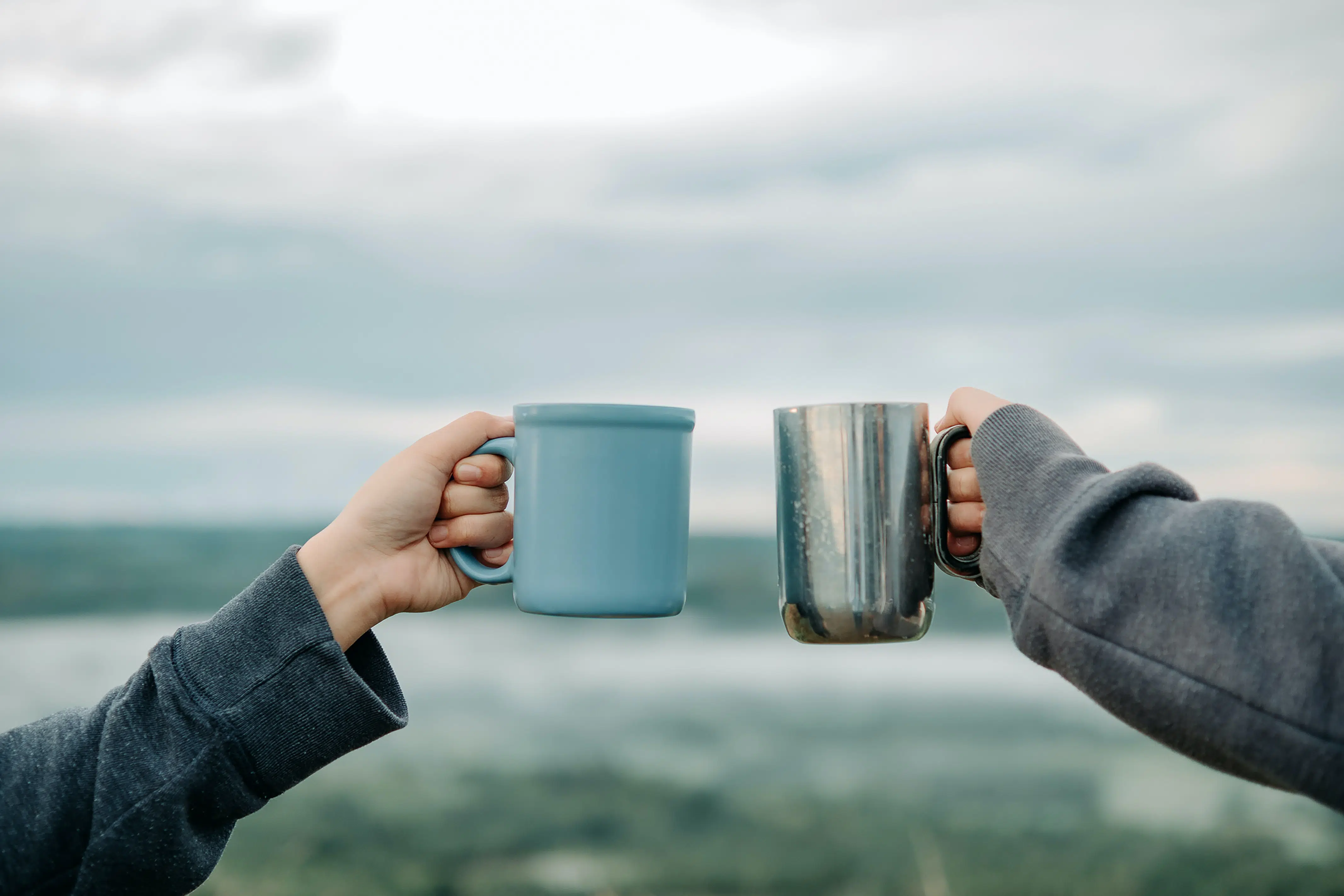 two hands holding mugs in the air.