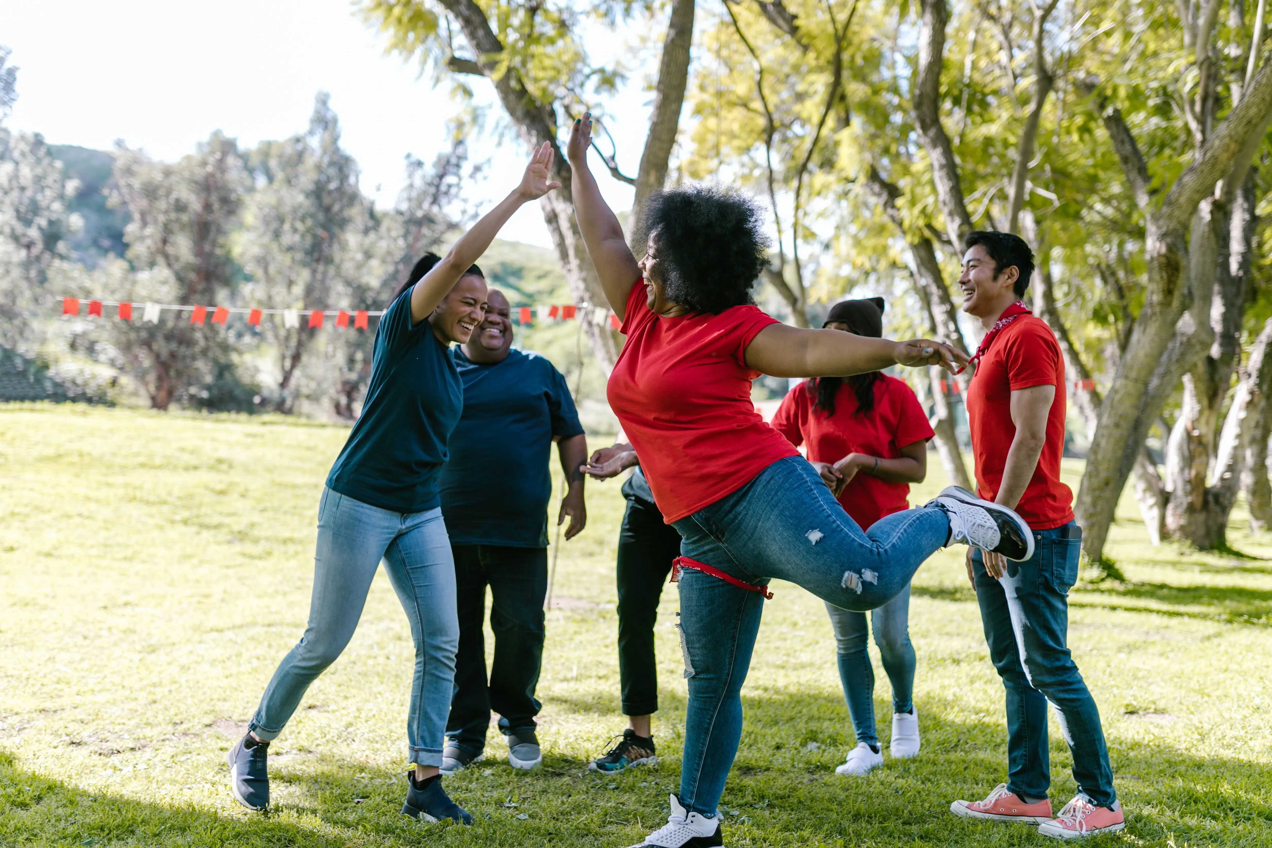 six individuals in a park cheering each other on and high-fiving.