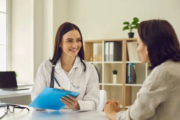 medical professional reviewing paperwork on clipboard with another woman.