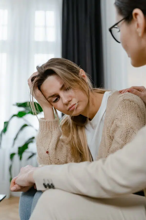 woman looking sad with head in hand talking to a therapist.