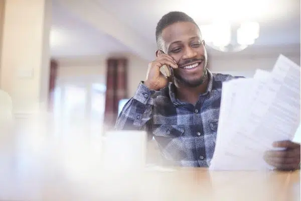 man sitting and talking on phone looking at paperwork.