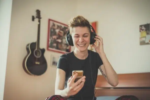 woman happy sitting in room listening to music on headphones.