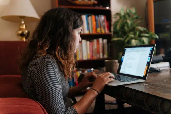 woman sitting on floor working on laptop at a coffee table.