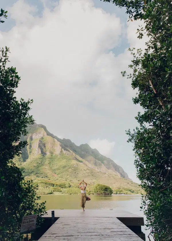 beautiful mountain view with dock leading into lake and a person doing a yoga pose at the end of the dock.