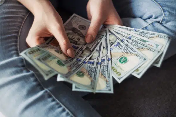 hands holding fanned out hundred dollar bills.