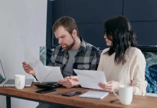 couple sitting reviewing paperwork and looking confused.