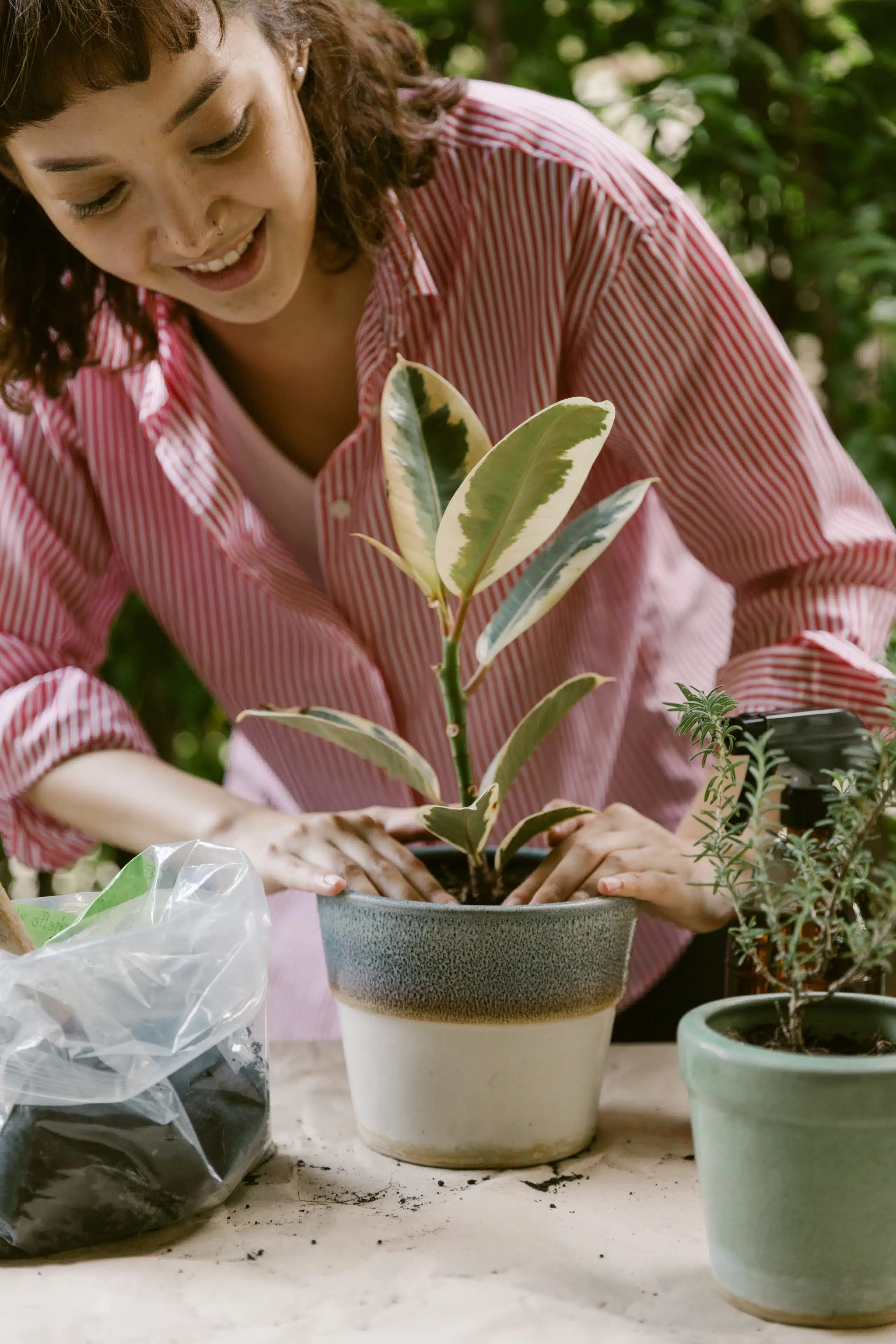 woman smiling and looking at her potted plant.