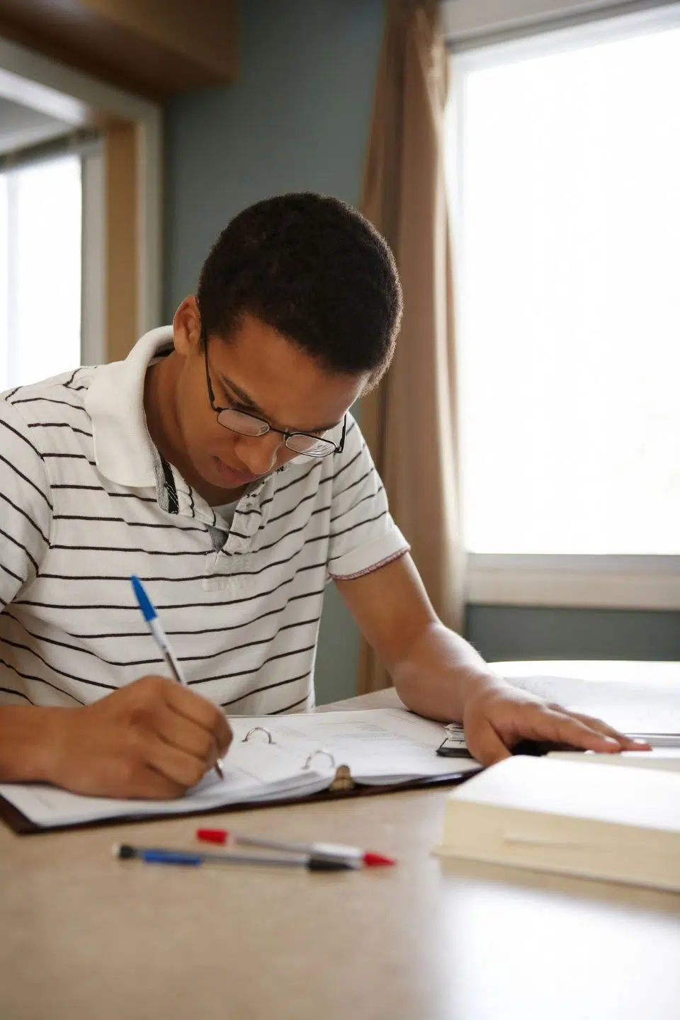 young man writing and studying at a table.