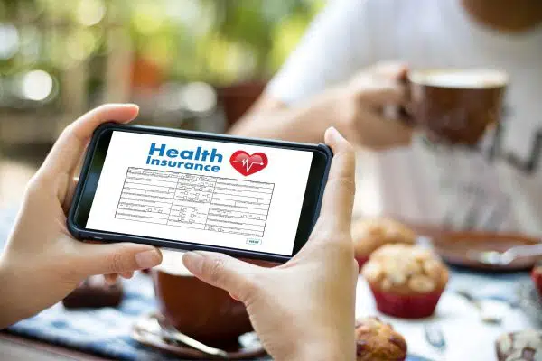 hands holding a cellphone with health insurance info on the screen.