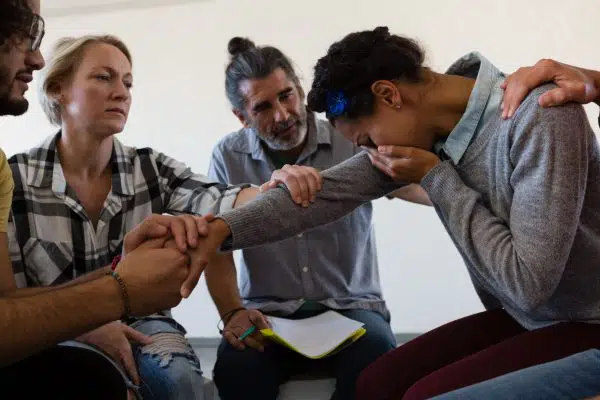 group therapy session, people offering support to woman crying.
