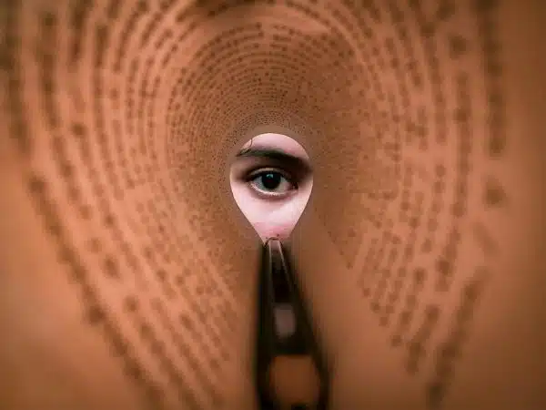 eye looking through a rolled piece of paper with writing on it.