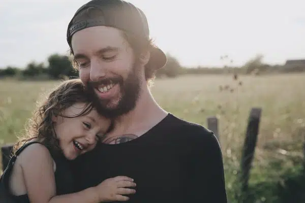 man holding young daughter, both laughing.