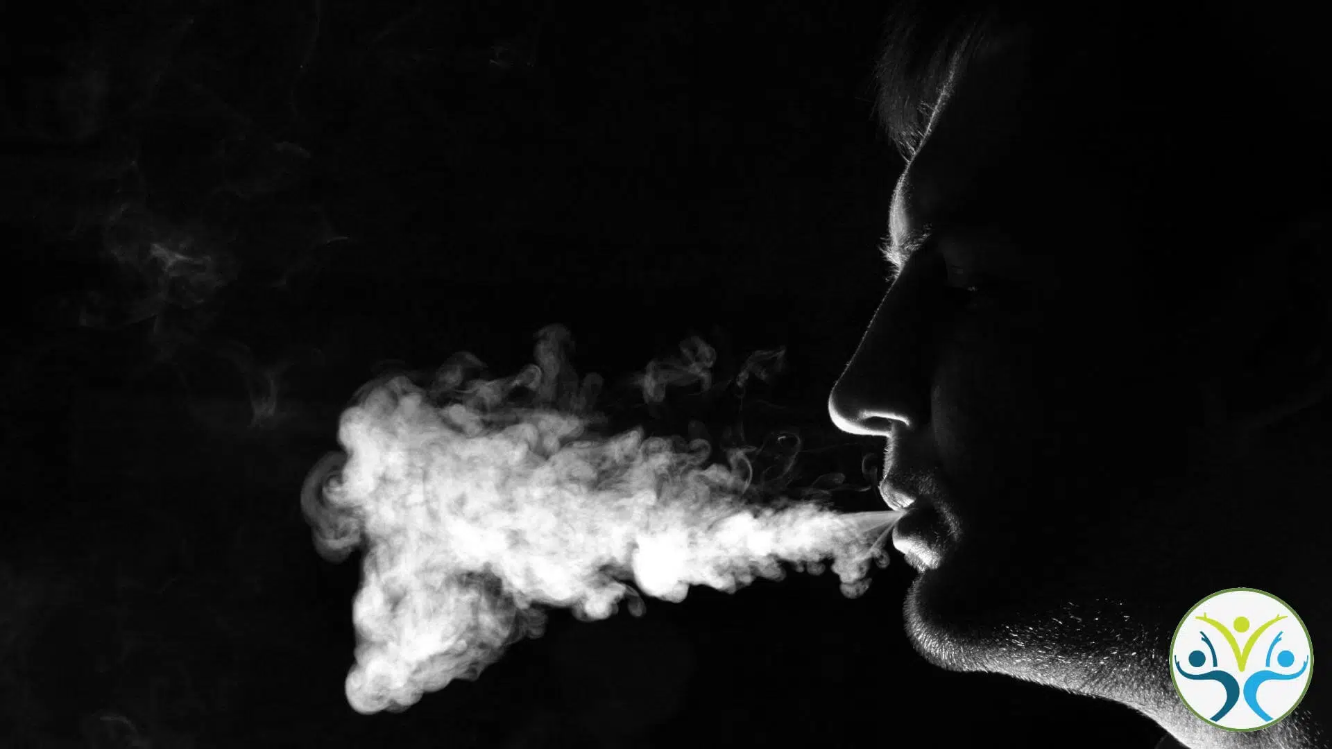 black and white silhouette of a person's profile blowing smoke out of smoke.