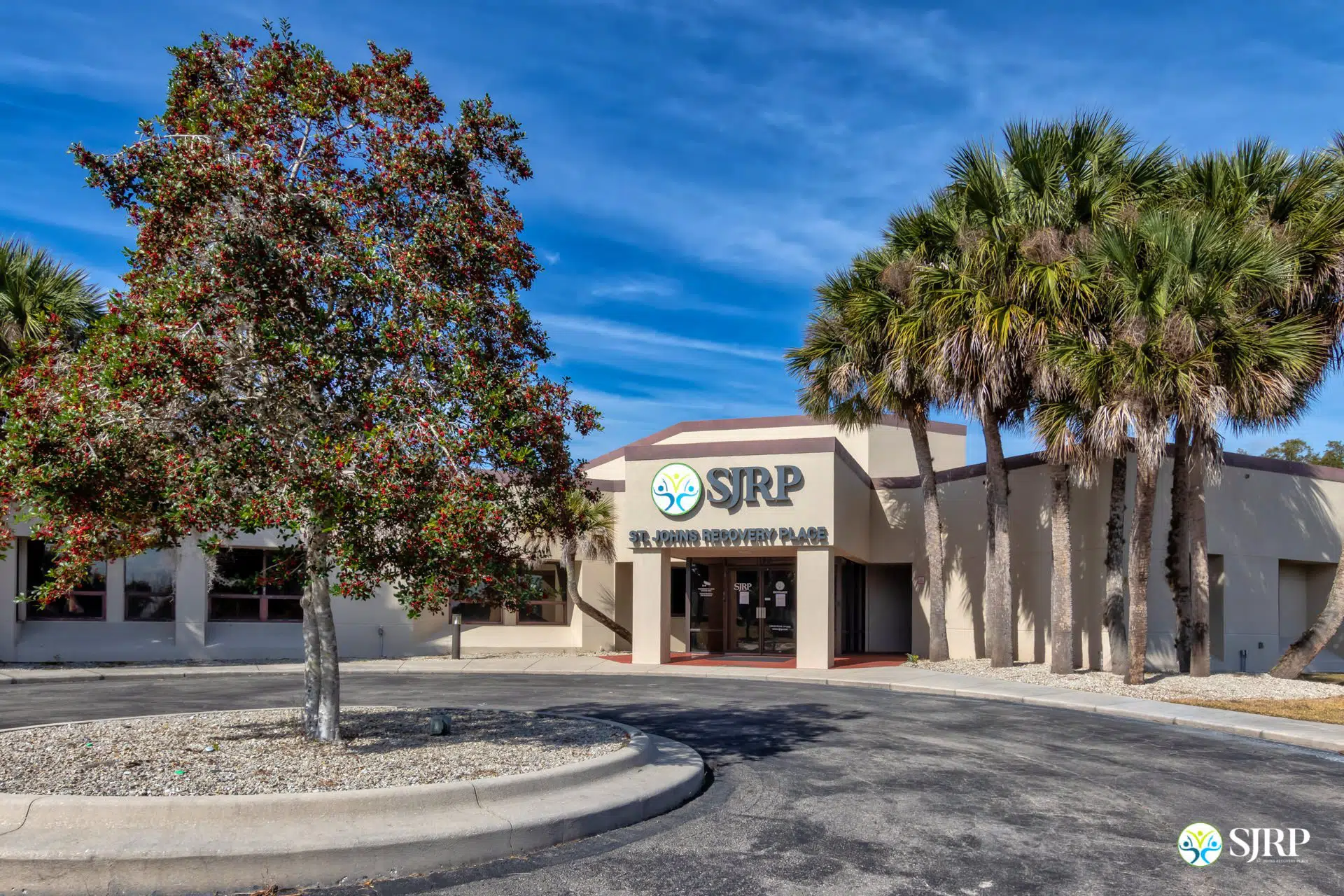 Exterior front entrance of SJRP with palm trees and blue sky.