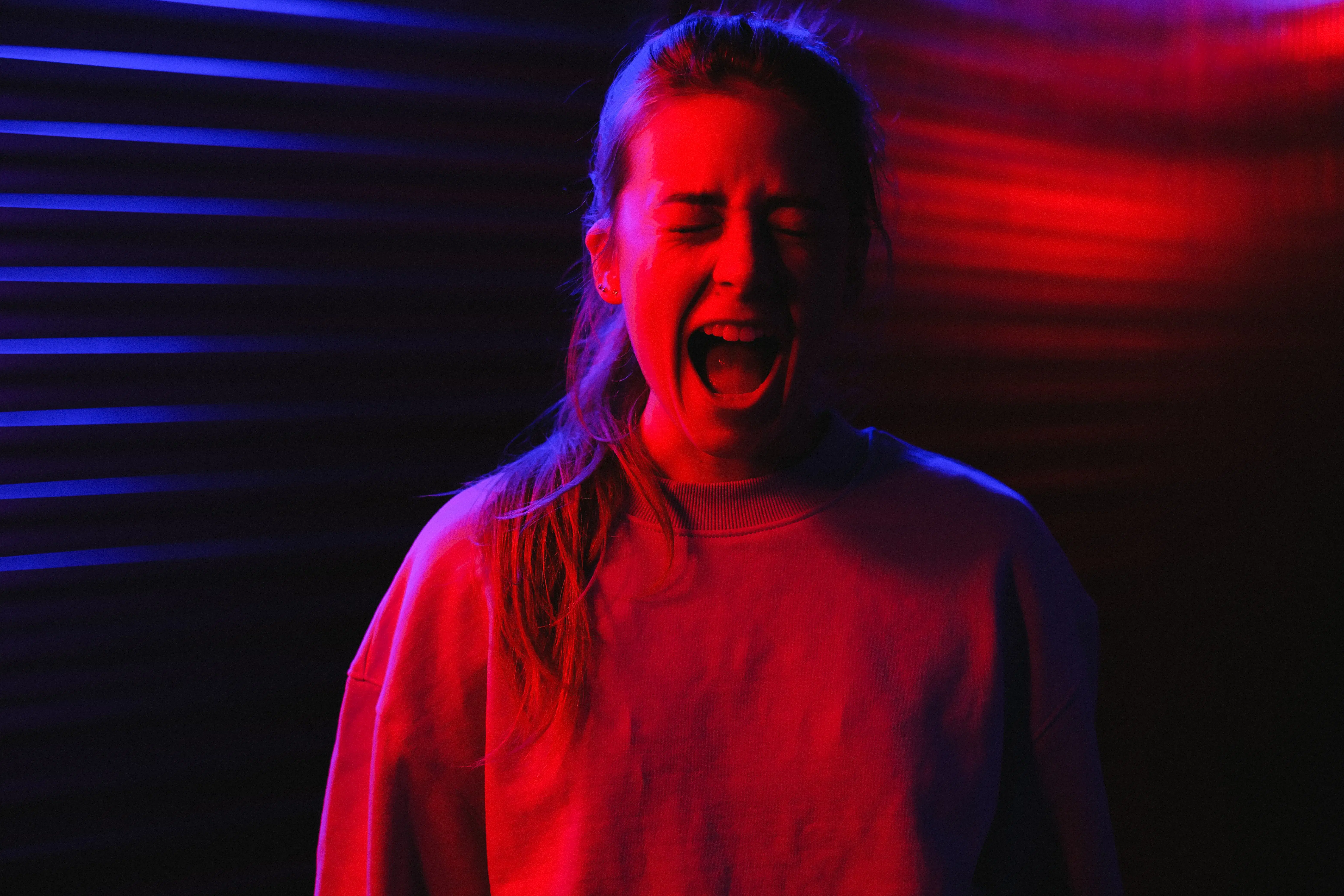 girl standing and screaming in a red-tone light.