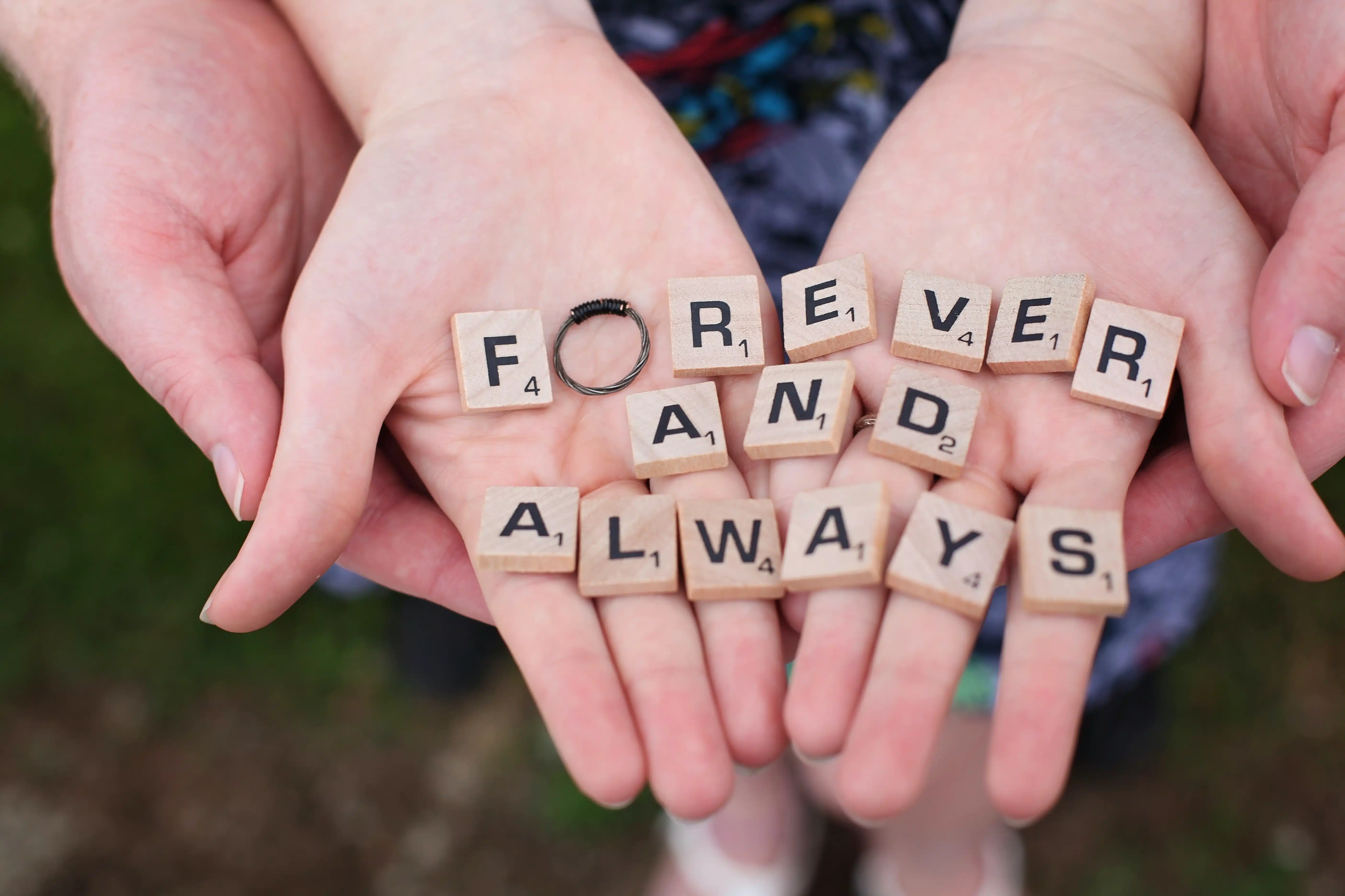two sets of hands with scrabble letters laid out that read "forever and always."